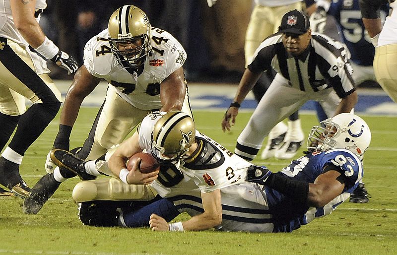 El exterior defensivo de los Potros de Indianápolis Dwight Freeney (d) derriba al mariscal de campo Drew Brees (i) de los Santos de Nueva Orleans