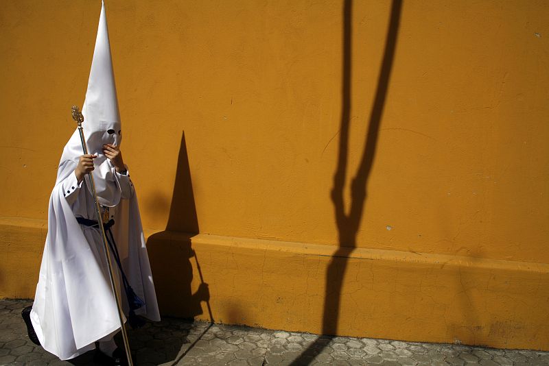 A penitent walks to church before taking part in the procession of the La Paz brotherhood during Holy Week in Seville