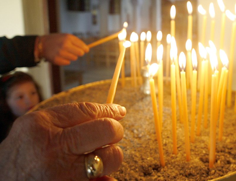 Albanian Orthodox believers light candles during an Easter service at a church in Tirana