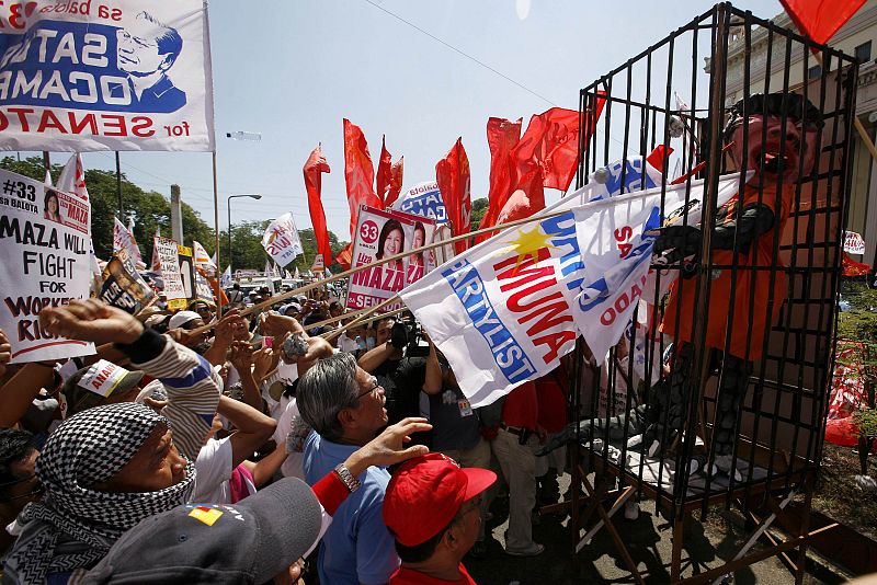 Protesters hit an effigy of Philippine President Gloria Macapagal Arroyo behind bars during their commemoration of International Workers' Day in Manila