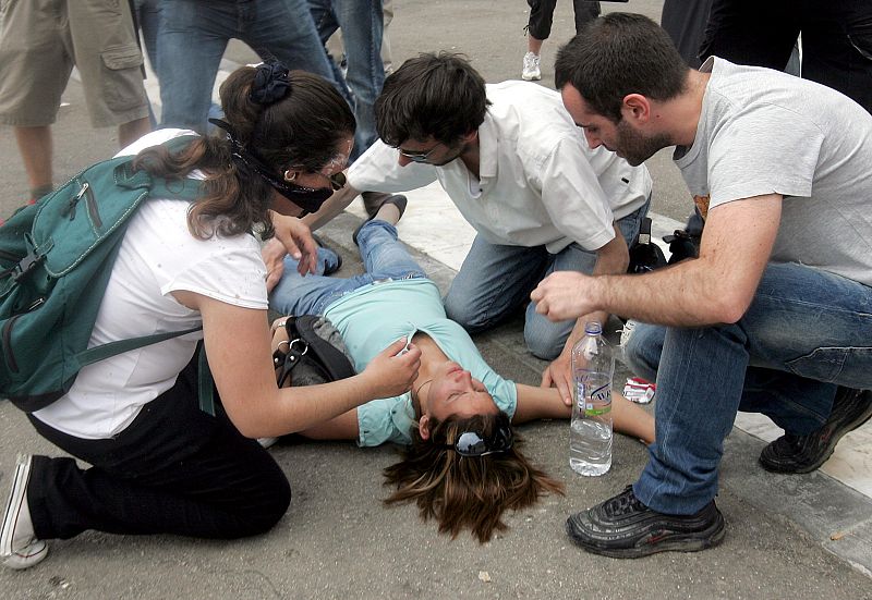 Varias personas atienden a una joven que ha resultado herida en los actos de protestas llevados a cabo este miércoles frente al Parlamento griego en Atenas.