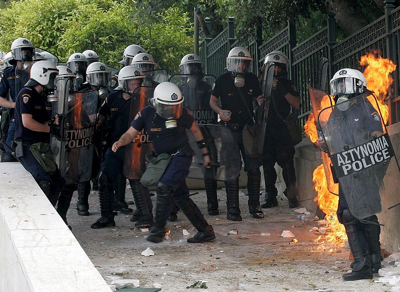 Varios agentes de la policía antidisturbios de Grecia reciben el impacto de un cóctel molotov.