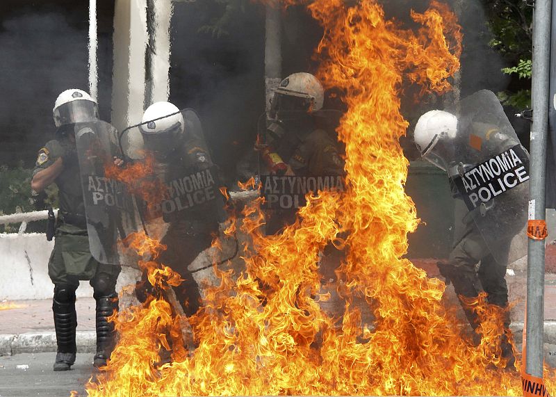 Varios policías griegos rodeados por las llamas de los cócteles molotov.