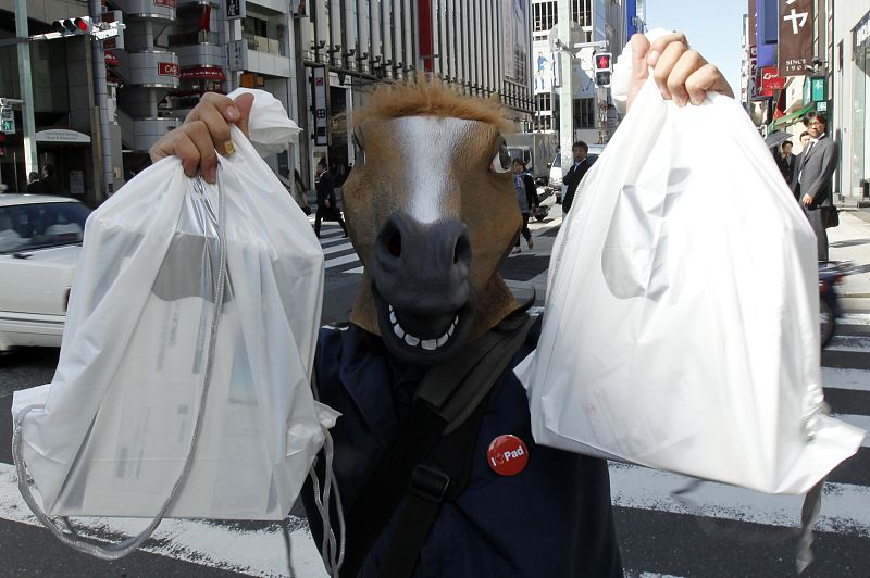 A man wearing a horse mask poses with his iPads after he bought them at an Apple store in Tokyo