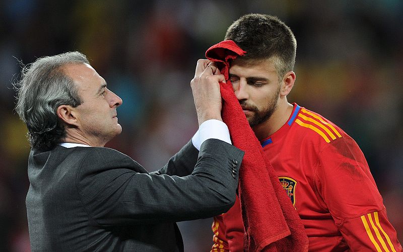 El defensa Gerard Piqué es atendido en la banda, tras haberse hecho un corte en la ceja mientras disputaba un balón.