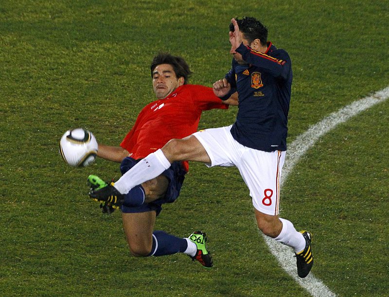 El chileno Estrada pugna por el balón con el jugador español Xavi.