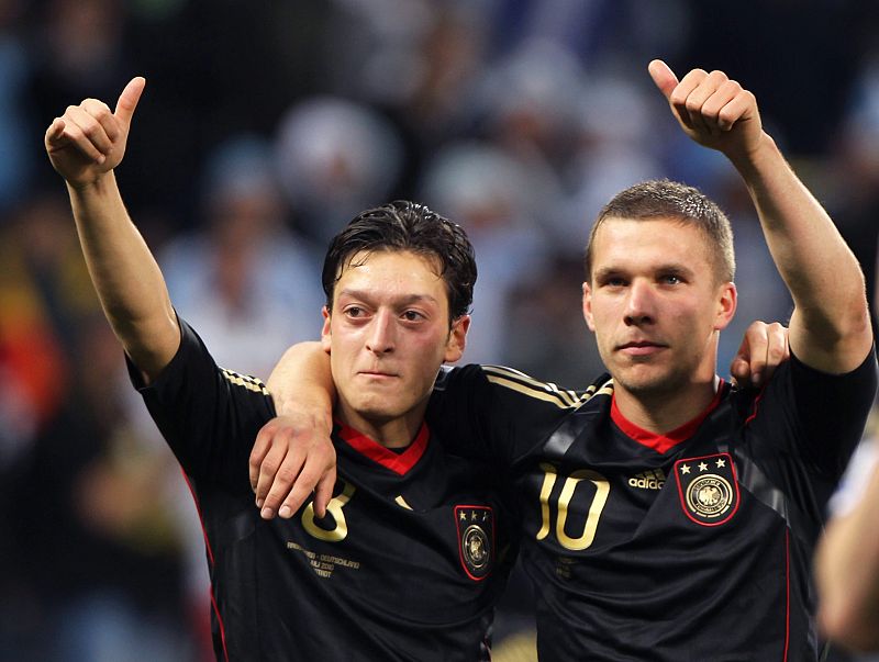 Los alemanes Özil (izquierda) y Lukas Podolski, saludan a los aficionados despues de que Alemania derrotara a Argentina por 4-0