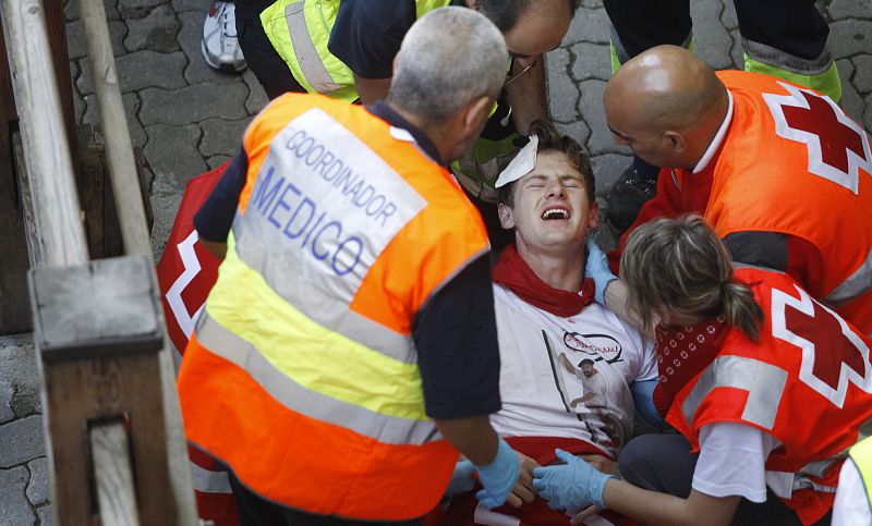 An unidentified runner is attended by emergency services on the first day of the running of the bulls during the San Fermin festival in Pamplona