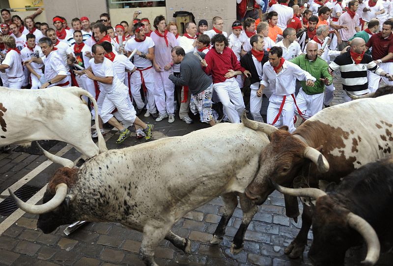 Runners take the Estafeta corner next to Penajara fighting bulls during the first running of the bulls on the second day of the San Fermin festival in Pamplona