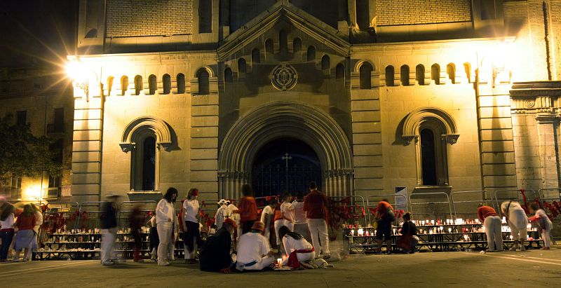 Un grupo de personas se quita sus pañuelos y los deja junto a las velas a la entrada de la Iglesia de San Lorenzo en Pamplona