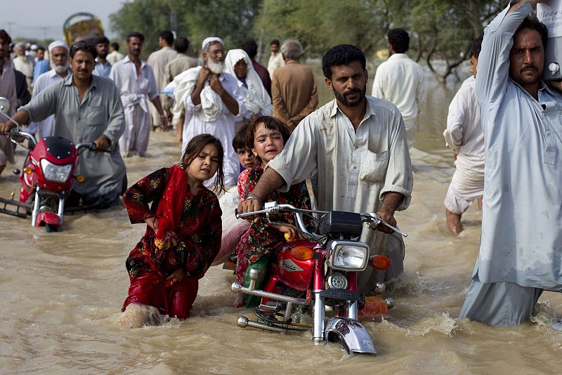 A man evacuates his children through waist-deep waters after heavy flooding in Nowshera, located in Pakistan's northwest Khyber-Pakhtunkhwa Province