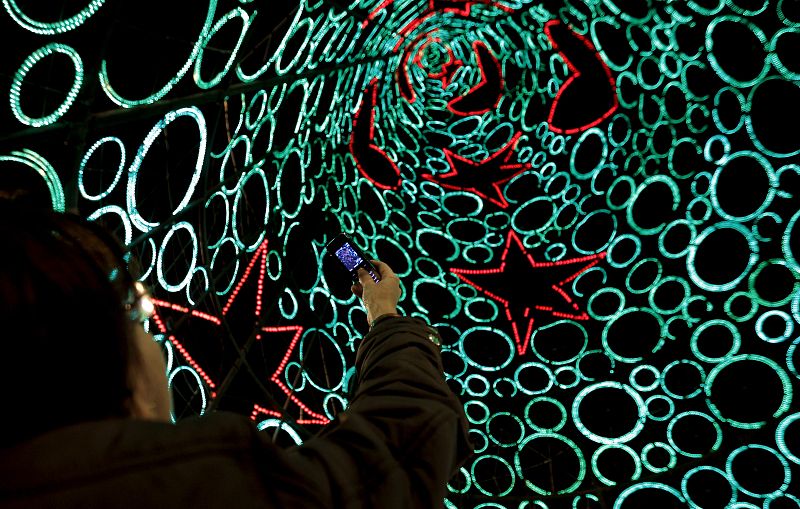 Una mujer fotografía la iluminación navideña de la Puerta del Sol de Madrid.