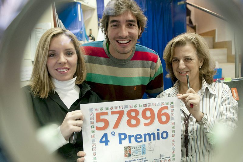 Responsables de la administración Doña Lola de Toledo muestran el número 57.896, uno de los cuartos premios del sorteo extraordinario de la lotería de Navidad, del que han vendido una serie, lo que supone 200.000 euros