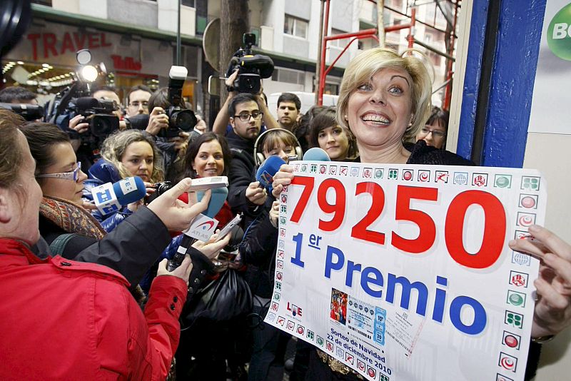 Yolanda Delgado, esposa del responsable de la administración 22 de Zaragoza, ante numerosos periodistas con un cartel con el número 79.250, premiado con el Gordo del sorteo extraordinario de la lotería de Navidad.