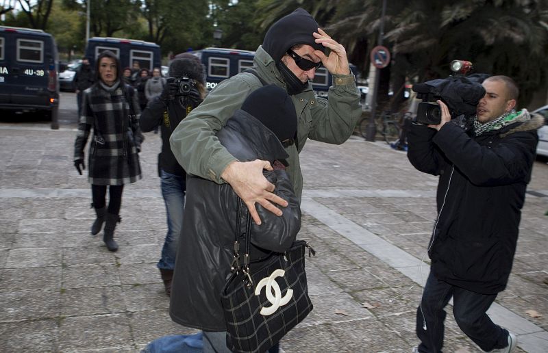 La madre del menor (con la cara tapada y agazapada entre el brazo de un acompañante), llega al edificio de la Audiencia de Sevilla.