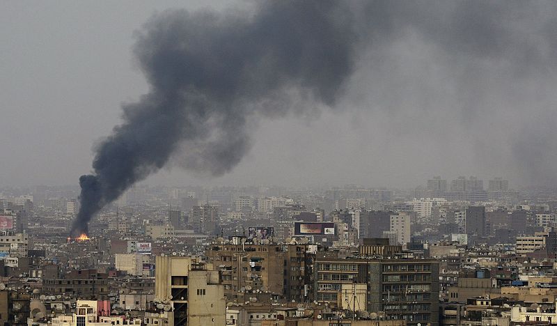 Una nube de humo se eleva por el cielo mientras las manifestaciones multitudinarias en contra del presidente egipcio Mubarak han provocado enfrentamientos en El Cairo.