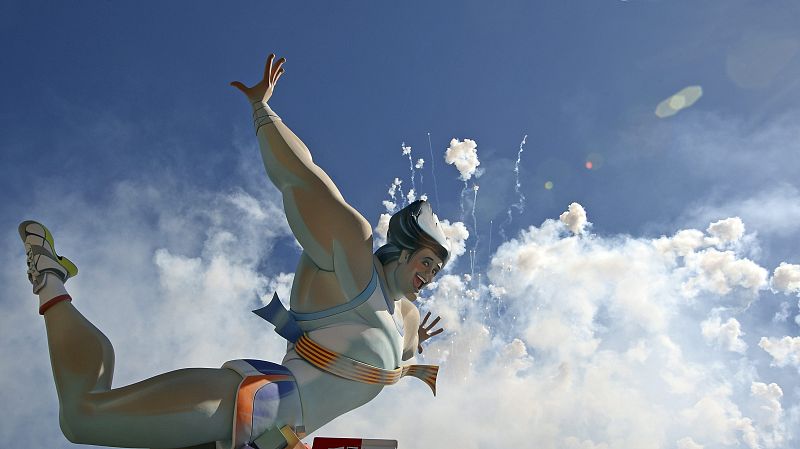 La figura principal de la falla municipal de la Plaza del Ayuntamiento se perfila contra el disparo aéreo de la mascletá.