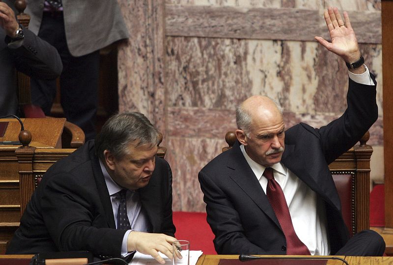 El primer ministro griego, Yorgos Papandréu, alza la mano para votar en presencia del ministro griego de Finanzas, Evangelos Venizelos, durante la votación de la ley que permite aplicar de forma inmediata el plan de ajuste para que el país siga recib