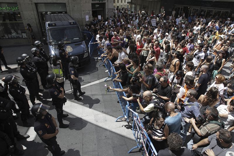 La marcha de "indignados" que partió este mediodía de la plaza de Oriente de Madrid retenida en la calle Preciados donde las vallas y el dispositivo policial impide su acceso a la Puerta del Sol.