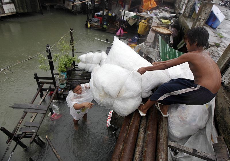 Filipinos recogen sus pertenencias de sus casas inundadas en Paranaque