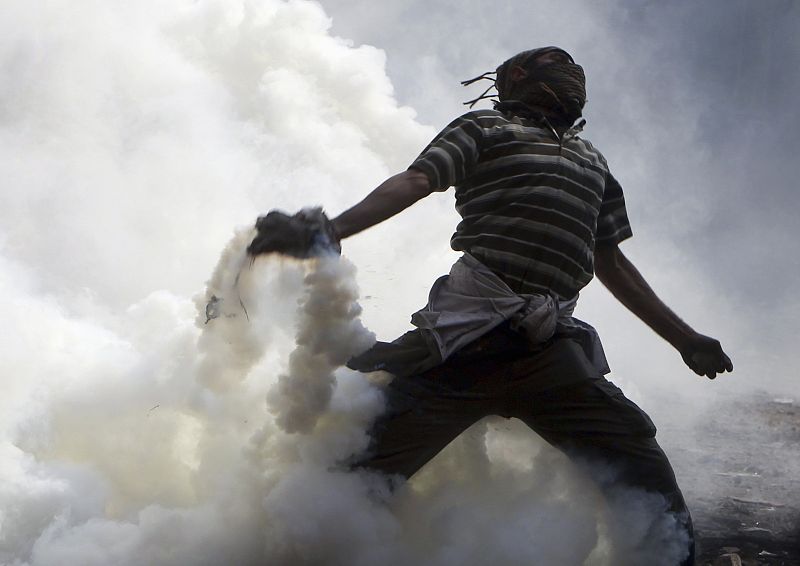 Un manifestante tira gases lacrimógenos contra los militares