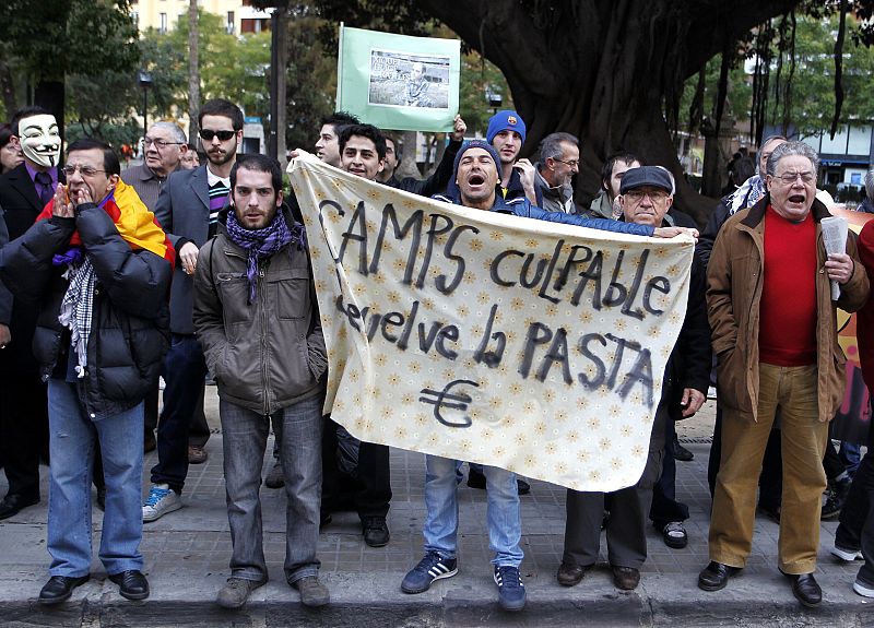"Camps, culpable, devuelve la pasta", reza una pancarta de algunso manifestantes que han increpado a los acusados a su entrada al TSJV. a