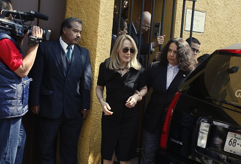 Lemus, wife of Mexican novelist Fuentes is helped by Saizar, director of National Council for Culture and Arts as they leave her home in Mexico City