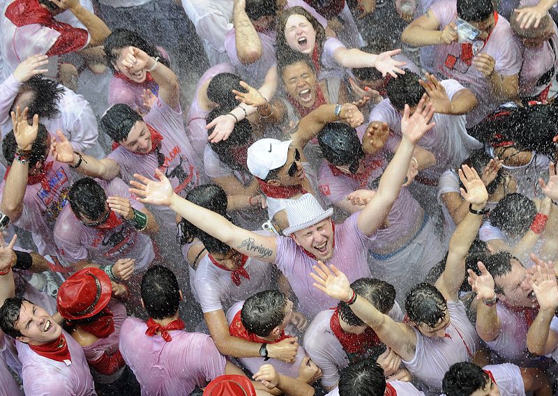 Los pamploneses y turistas tras el Chupinazo se lanzan agua y vino