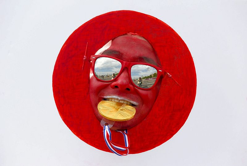 Un aficionado japonés vestido como la bandera de su país muerde una réplica de una medalla de oro durante la maratón masculina.