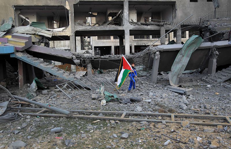 Un chico palestino con la bandera nacional entre los restos del Estadio Deportivo de la ciudad de Gaza