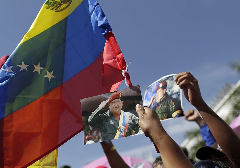 Chavistas asistentes al funeral de estado sostienen imágenes del difunto presidente Hugo Chávez