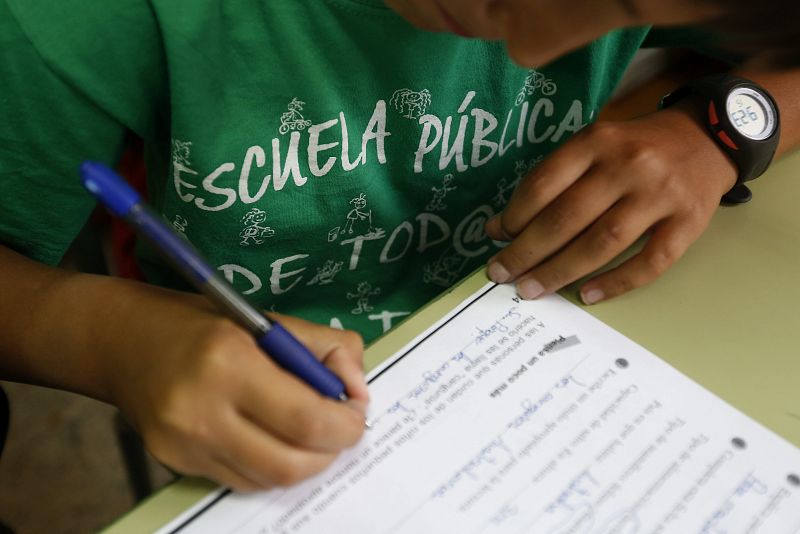Un alumno del Colegio Joaquín Costa de Madrid rellena una ficha con la camiseta a favor de la escuela pública