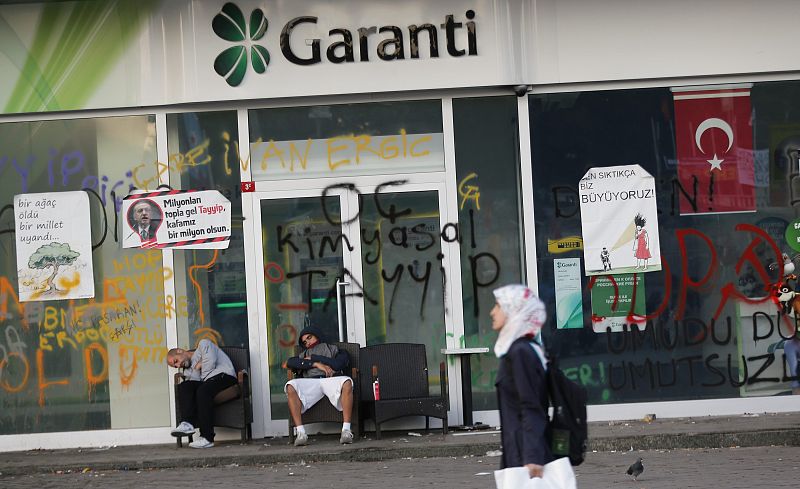 Tras una noche de disturbios, dos manifestantes descansan ante una sucursal de Garanti Bank en Estambul.