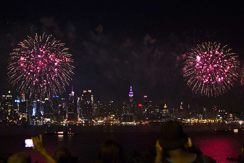La gente observa los fuegos artificiales sobre el río Hudson, con el horizonte de Nueva York alfondo, durante la celebración del Día de la Independencia