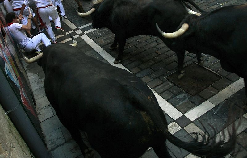 Runners fall in the path of Dolores Aguirre Ybarra at the Estafeta corner during the second running of the bulls of the San Fermin festival in Pamplona