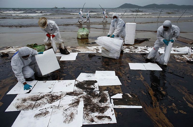 Los soldados colocan láminas de un papel especial para limpiar las playas del vertido de petróleo de la empresa PTT Global Chemical Pcl que afecta el este de Tailandia.