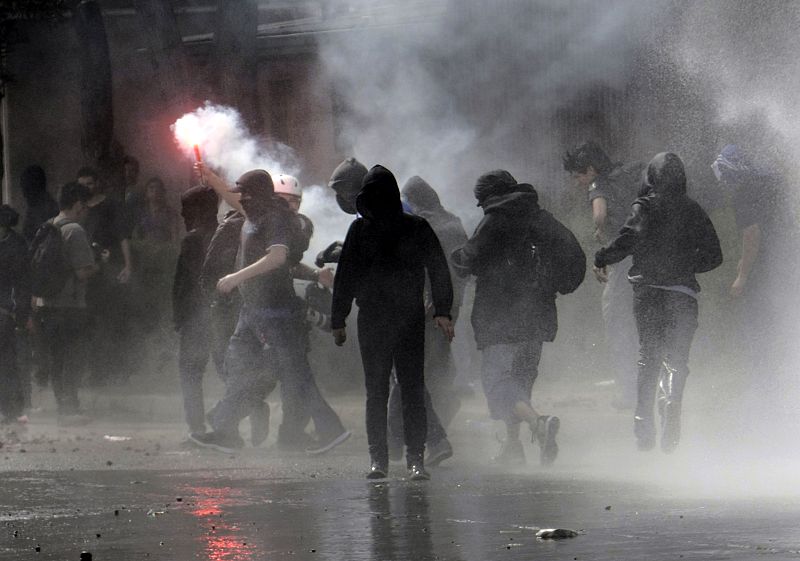 Un grupo de encapuchados enciende bengalas durante su enfrentamiento contra los antidisturbios chilenos en las protestas en conmemoración del golpe de Estado de Pinochet que acabó con el Gobierno y la vida de Salvador Allende en 1973