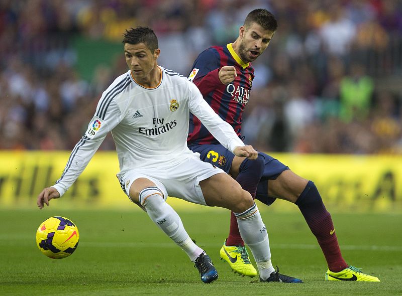 El delantero portugués del Real Madrid Cristiano Ronaldo lucha un balón con el defensa del F.C. Barcelona Gerard Piqué.
