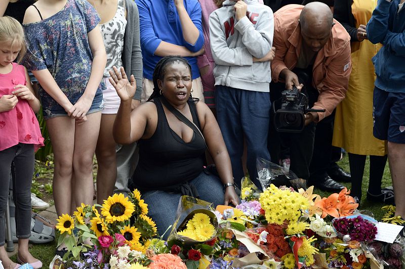 Una mujer reza a las puertas de la última residencia de Mandela tras conocer su muerte