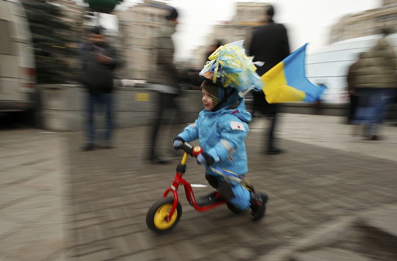 A young child carrying a Ukranian flag uses a scooter during a pro-European integration rally in Independence Square in Kiev