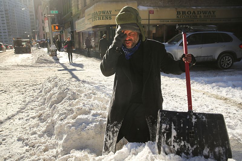 Un indigente retira nieve de la calle en Nueva York