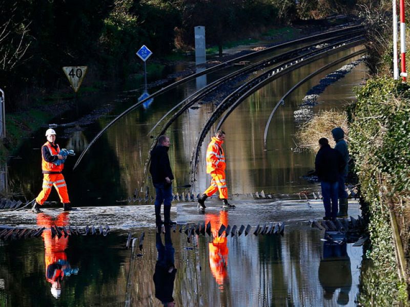 Trabajadores ferroviarios cruzan las vías inundadas por el Támesis en las cercanías de Datchet, al sur de Inglaterra.