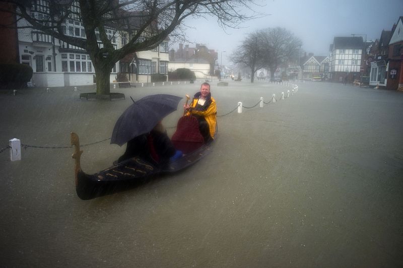 A couple paddles in a gondola while posing for media, through the flooded central square in the village of Datchet in Berkshire