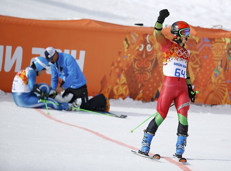 Morocco's Lamhamedi celebrates after crossing the finish line as injured South Korea's Kyung is attended to, after the first run of the men's alpine skiing giant slalom event in the Sochi 2014 Winter Olympics at the Rosa Khutor Alpine Center