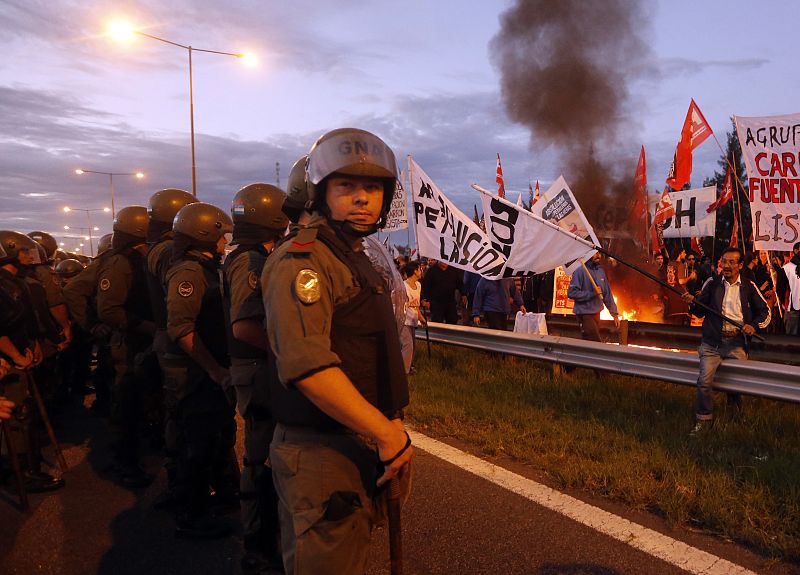 Varios agentes tratan de frenar al grupo de manifestantes que bloquea la autopista