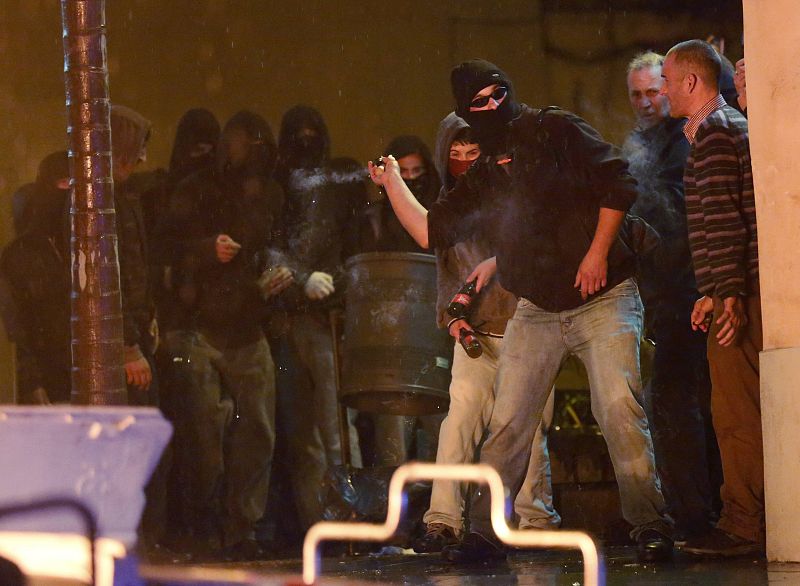 Un hombre arroja un petardo durante los disturbios