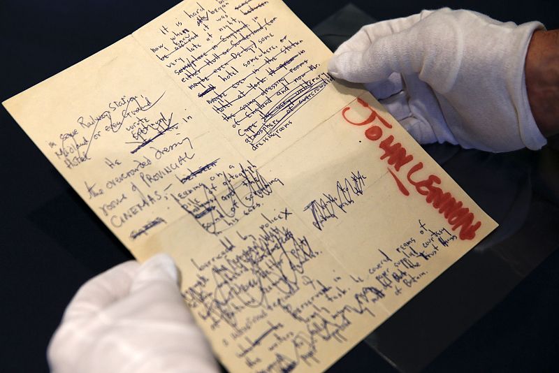 Un empleado de Sotheby's sostiene uno de los manuscritos de John Lennon a la venta en Nueva York