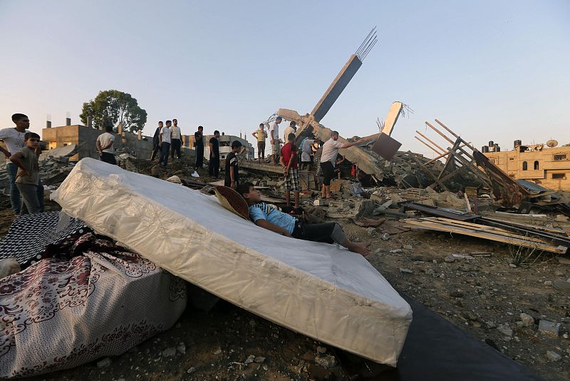 Un joven palestino descansa sobre un colchón entre los escombros de una casa destruida durante la ofensiva israelí en la ciudad de Gaza.