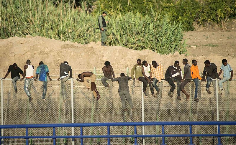 Alguno de los inmigrantes subidos a la valla presentan heridas.