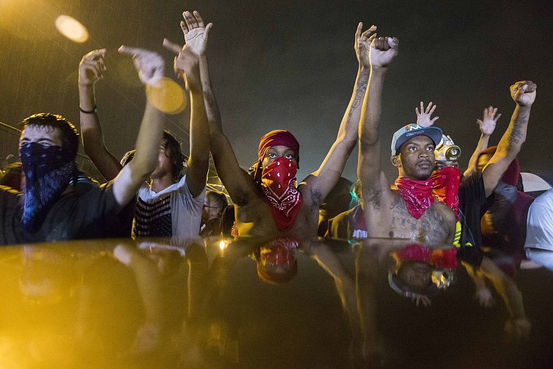 Protesters gesture as they stand in the street in defiance of a midnight curfew in Ferguson, Missouri